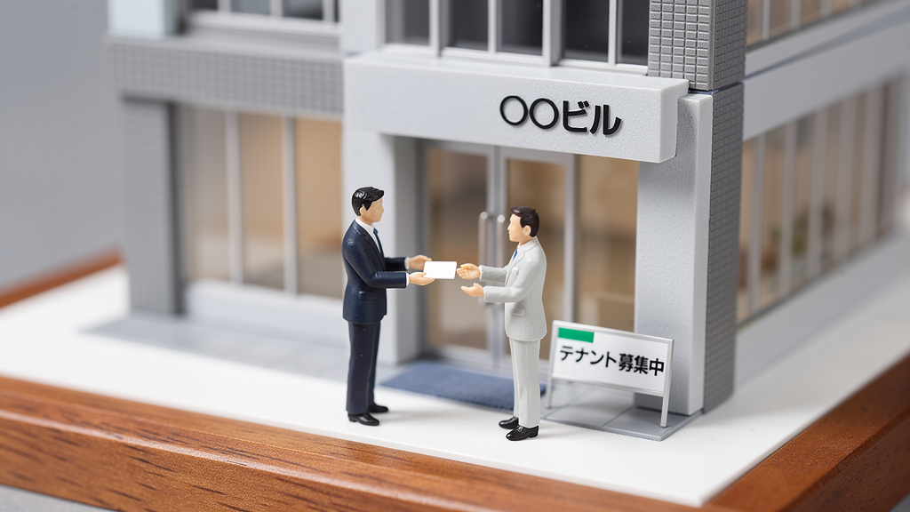 ビルの模型の前で、営業マンと大家さんの形をした人型模型が名刺交換しているイラスト