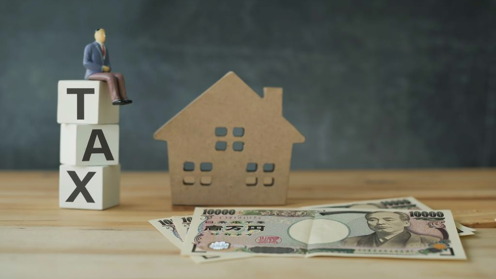 家の模型と、お金が机に置かれているイラスト